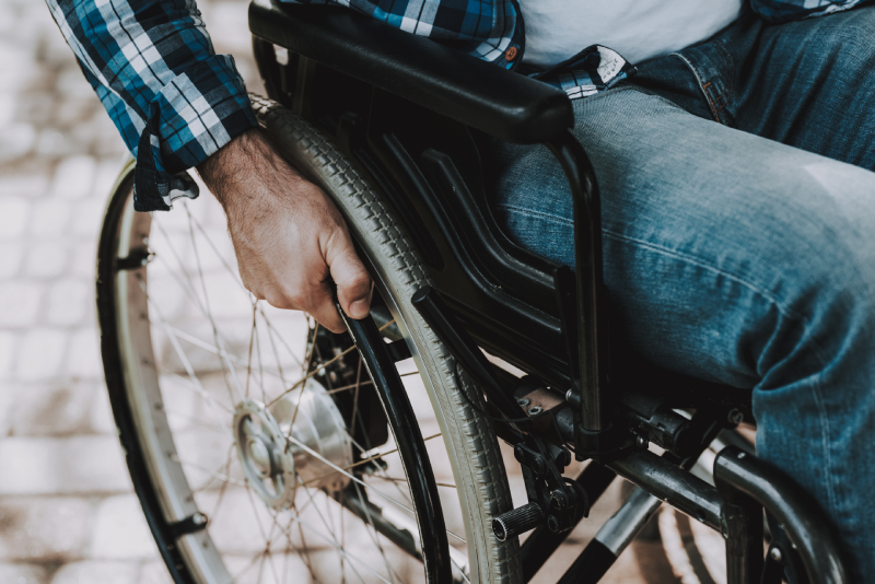 Close up. Disabled Man on Wheelchairs in Park. Disabled Young Man. Relaxing in Summer Park.
