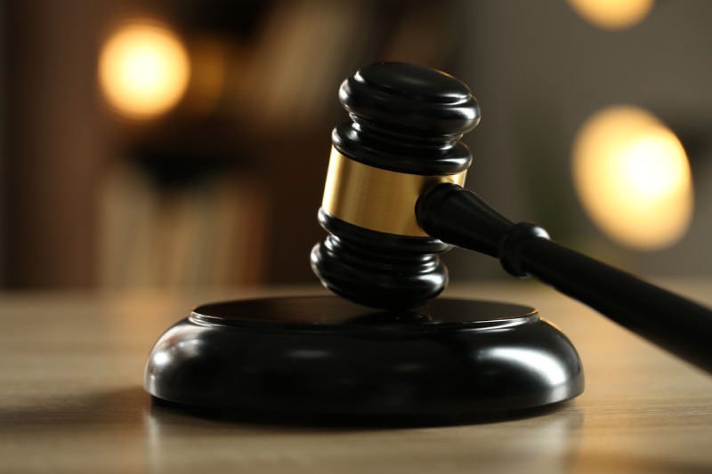 Judge's gavel on wooden table against blurred background, closeup