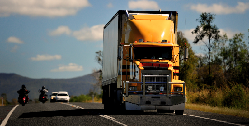 Yellow Truck riding trough an Australian highway at golden hour.