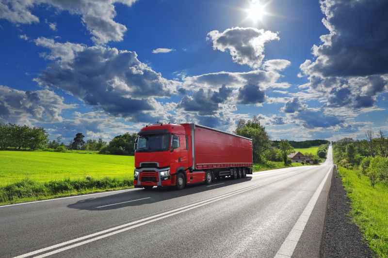 Cargo truck driving through landscape at sunset