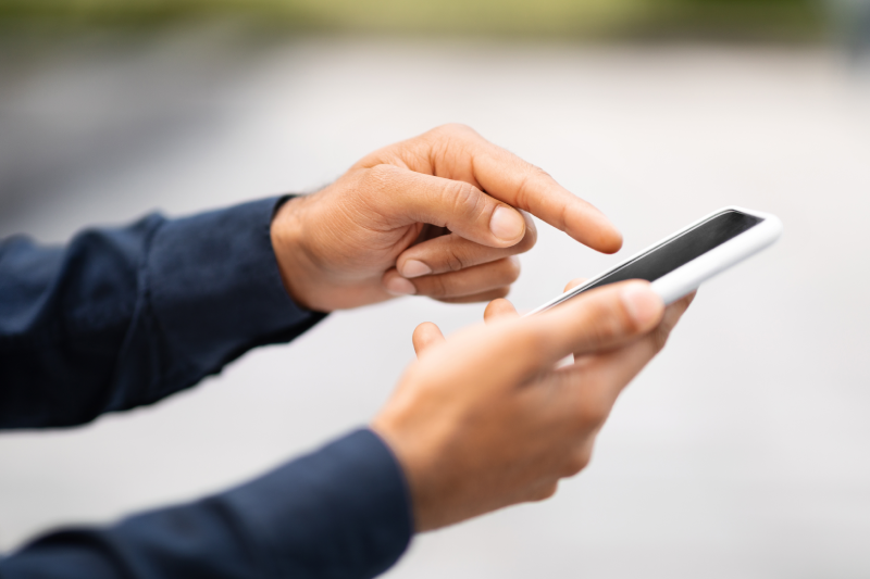 Cropped of man hands holding cell phone with black screen outdoors. Unrecognizable businessman using smartphone