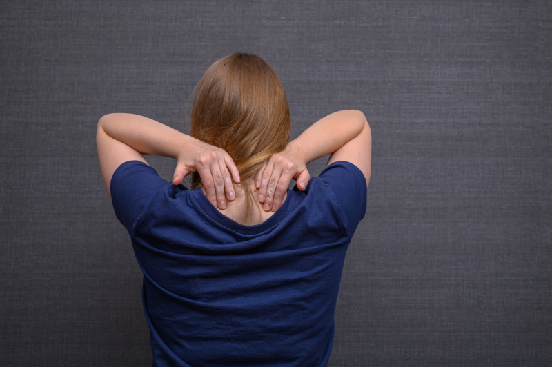 Neck pain and stiffness, woman holds her neck