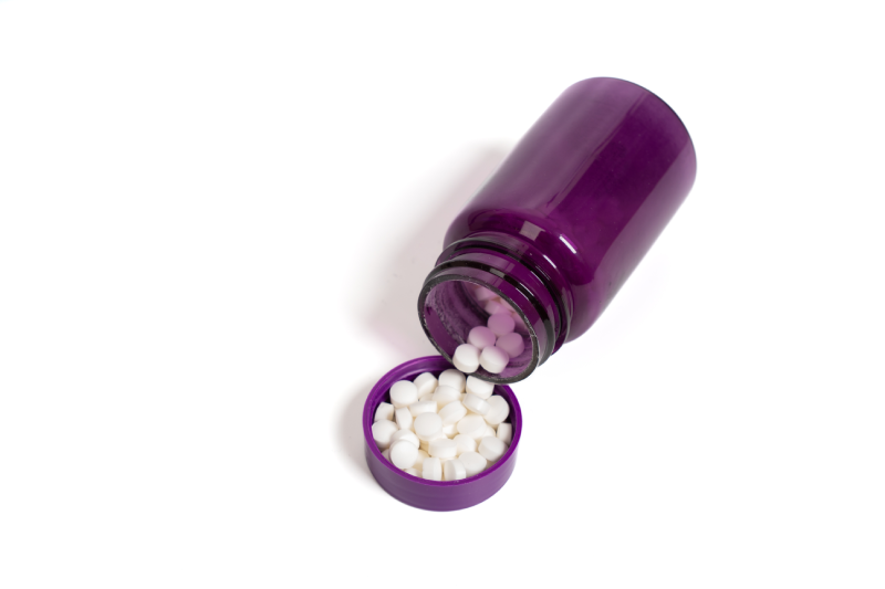 Open purple pill bottle with white tablets on isolated white background.