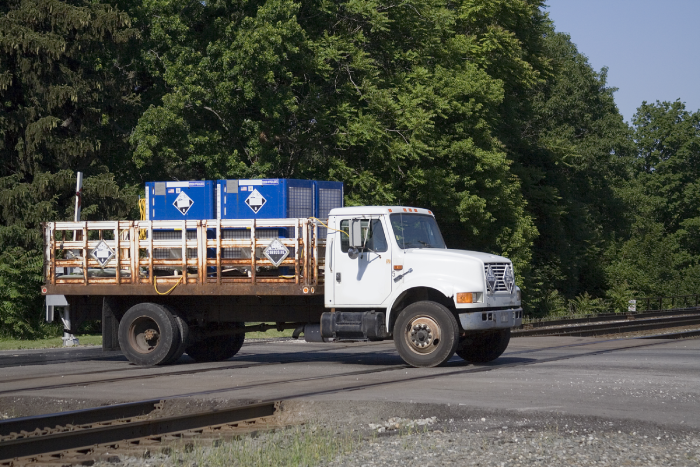 Truck transporting hazardous chemicals crossing a railroad track.