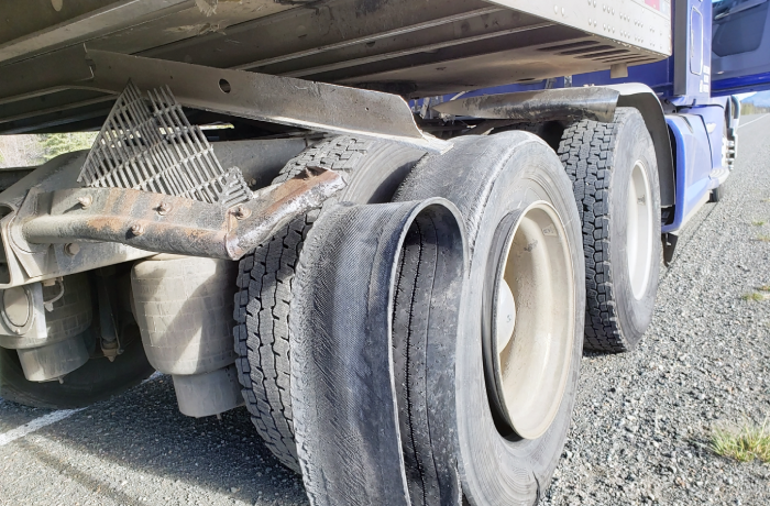 Damaged 18 wheeler semi truck burst tires on the shoulder.