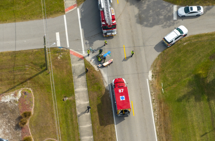 Victim of car accident on medical stretcher. First responders responding to car hit cyclist on street.