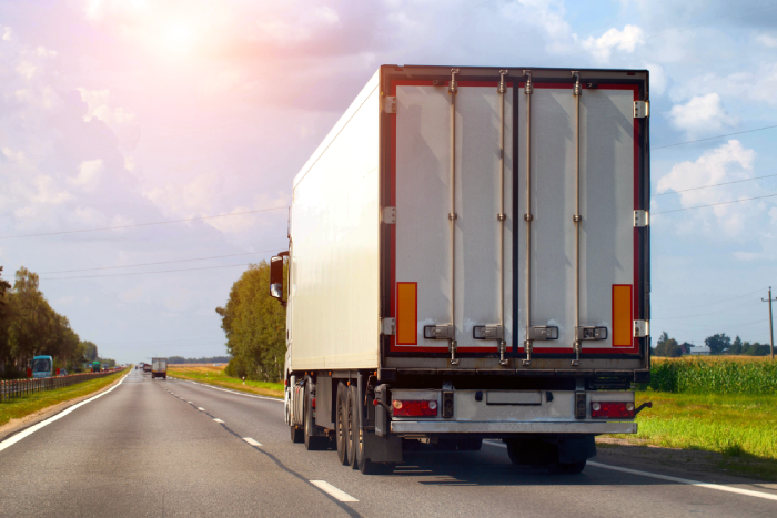Transportation of consolidated cargo for online stores by trucks with semi-trailers along the highway in the summer.