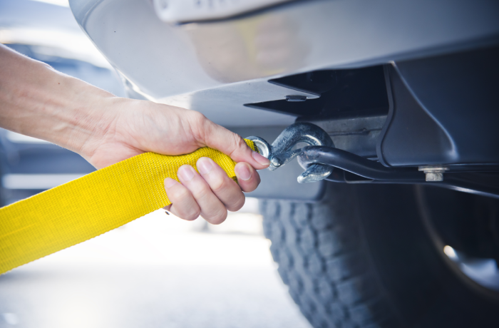 Hand holding yellow car towing strap with car, car towing, towing rope